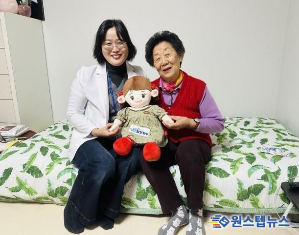 화성시동탄보건소 관계자와 독거 어르신이 AI 돌봄로봇 ‘효돌이’를 함께 들고 환하게 웃고 있다