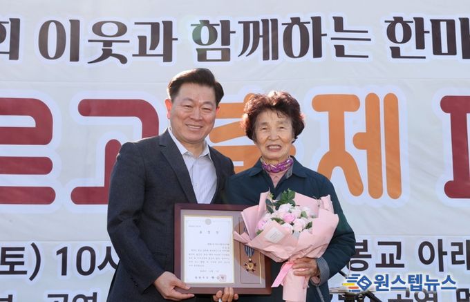 박승원 광명시장이 지난 1일 개봉교 아래 목감천 일대에서 열린 ‘제8회 광명2동 한마당 축제’에 참석해 어르신 환경봉사대 참여 어르신에게 시창 표창을 수여하고 기념사진을 촬영하고 있다.