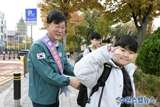 이민근 안산시장(사진 왼쪽)이 학현초등학교 앞에서 ‘스쿨존 어린이 교통안전 캠페인’을 진행하며 등교하는 어린이의 가방에 '홍이 키링'을 달아주고 있다.