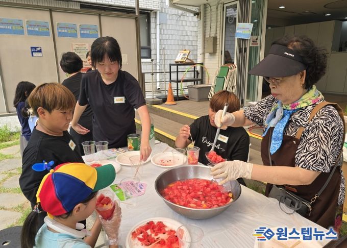 '우리마을 은빛 놀이터’프로그램에 참여한 어르신이 아이들에게 수박화채를 나눠주고 있다.