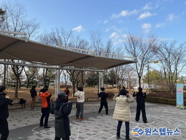 화성특례시 병점구보건소가 운영하는 비만 예방 프로그램 ‘온가족 공원체조’에 참여한 시민들이 공원에서 체조를 하고 있다