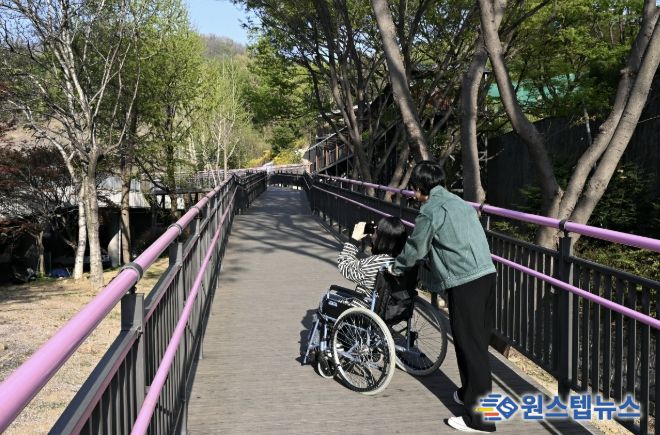 휠체어 이용객이 무장애 데크길을 이용해 진달래동산으로 이동하고 있다.