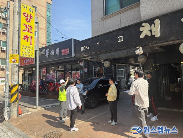 정명조 건축과장과 관계자들이 도로변 상가 간판의 안전 상태를 확인하며 현장점검을 하고 있다.